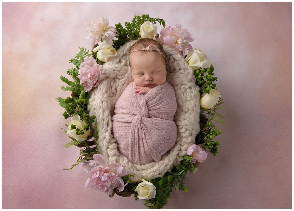 newborn in driftwood basket with flowers